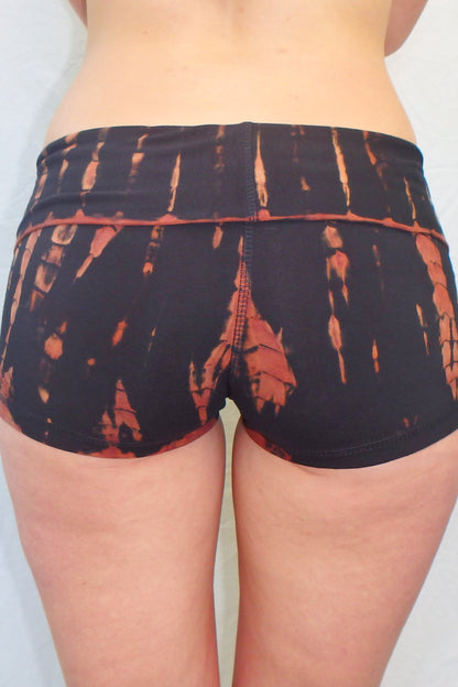 Fire tie dye yoga shorts are black with orange streaks. Have fold over waist band. Back view of curve hugging booty shorts shown.