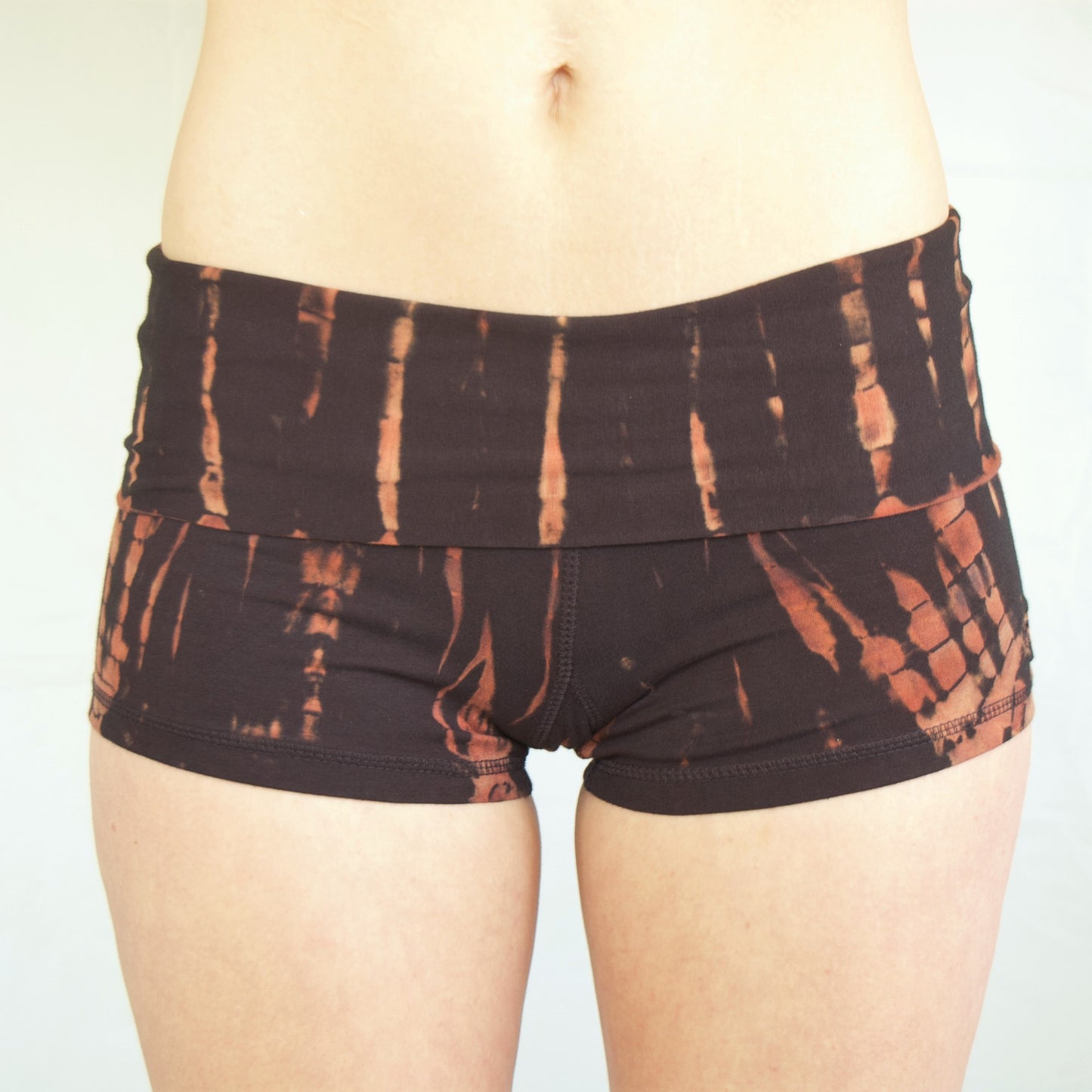 Lotus Tribe Clothing's curve hugging fire tie dyed short shorts are black with burnt orange highlights, have a fold over waist are soft and comfortable ethically made of 90% cotton 10% spandex.