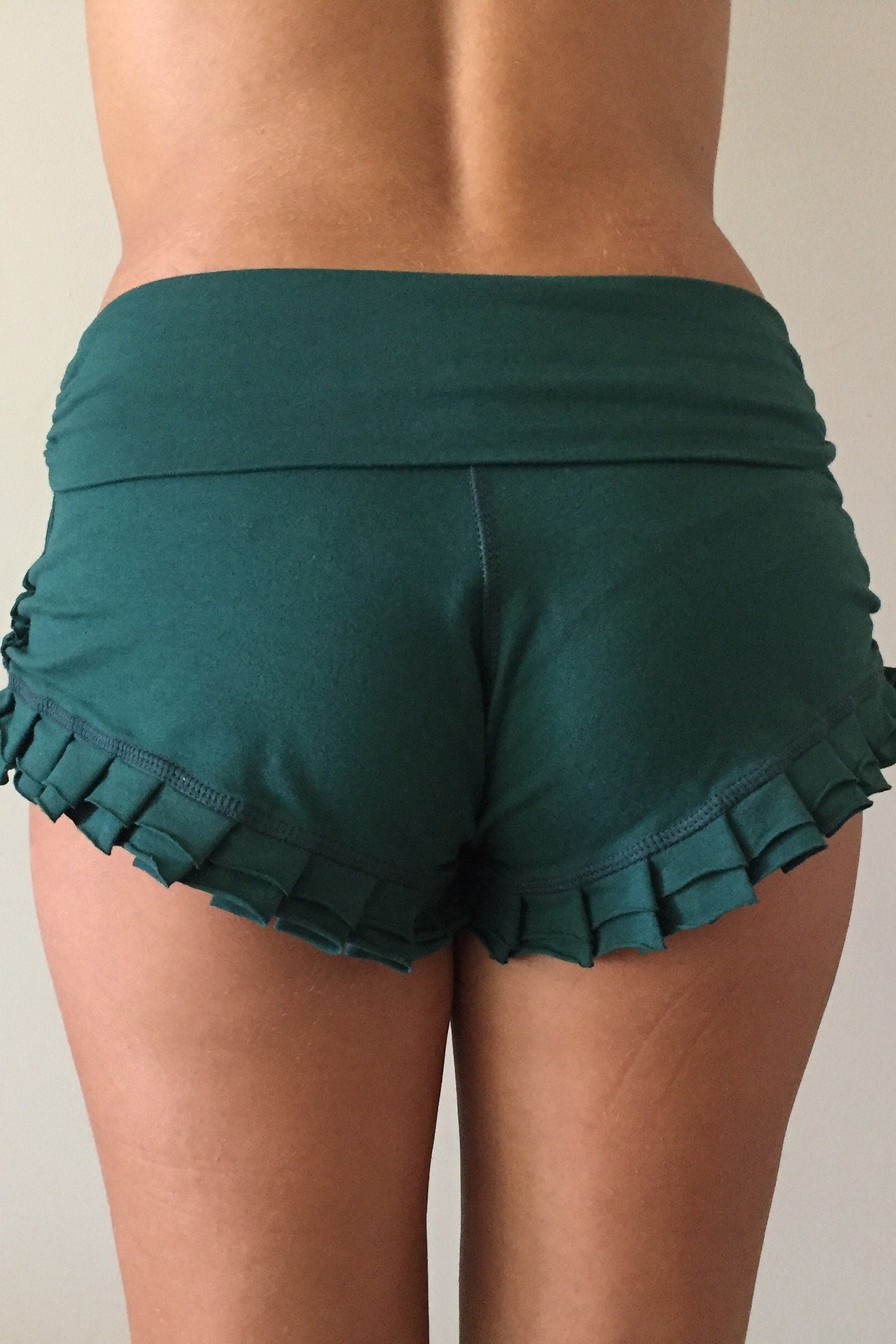 Back view of Forest green shorts with ruffles at bottom and fold over waist perfect for hot yoga or paired with your favorite top, also great for under a short dress.