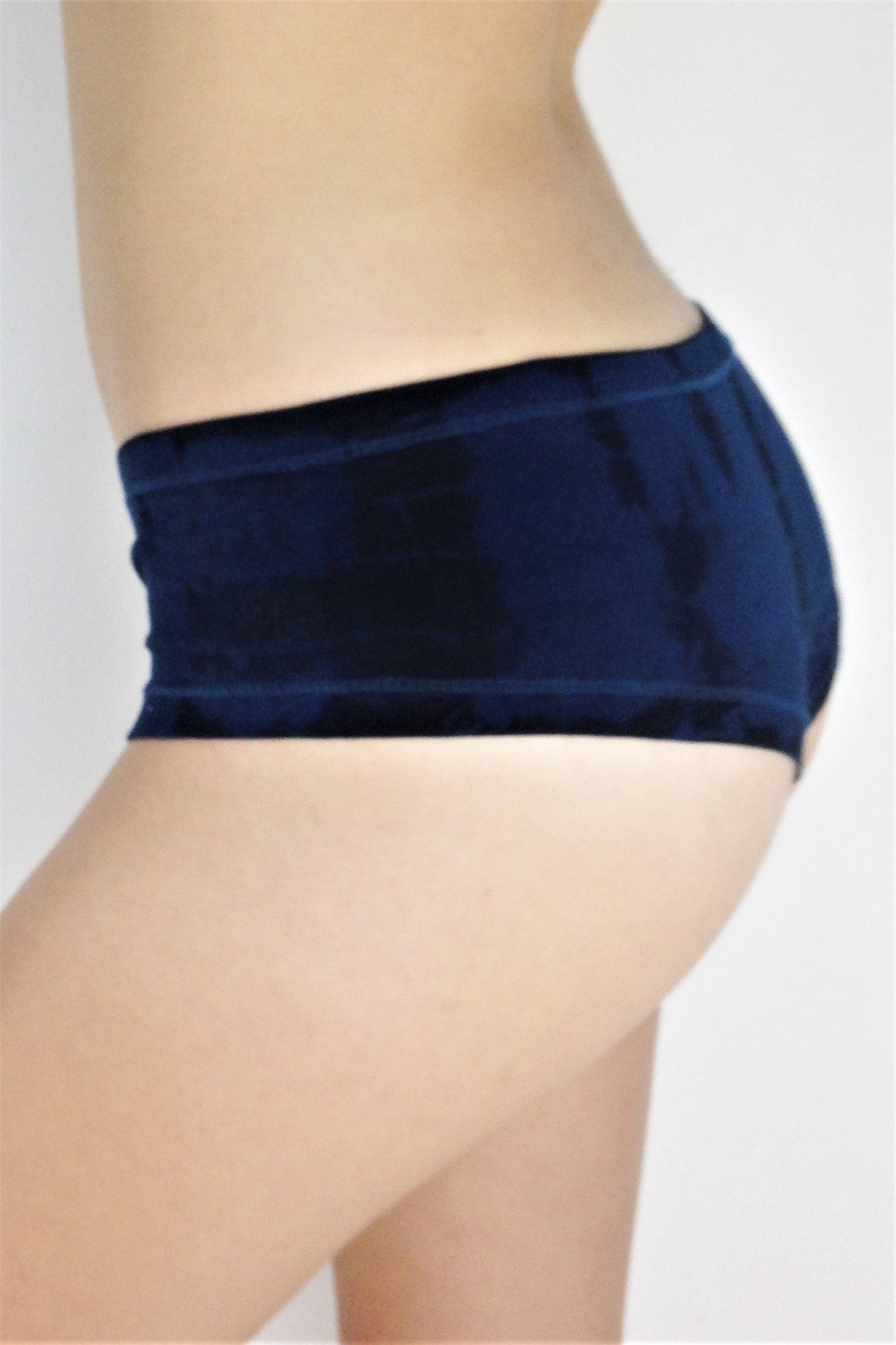 Side view of Midnight Tie Dye Cheeky Undies, dark blue tie dye with black highlights 90% cotton 10% spandex with small lotus flower embroidery detail on left leg