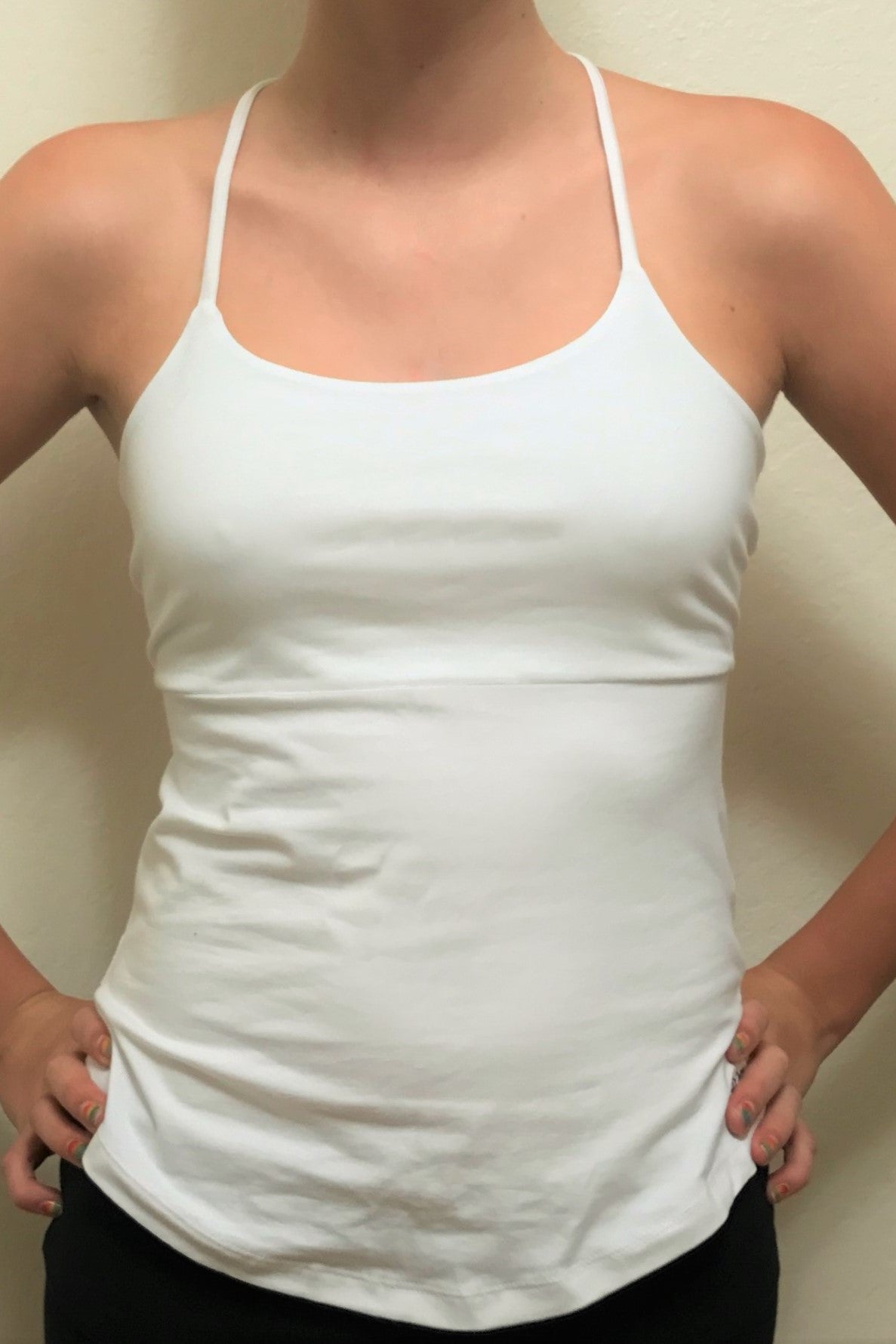 Front view of solid white tank top. Spaghetti straps, seam under the bust and rounded bottom edge. 