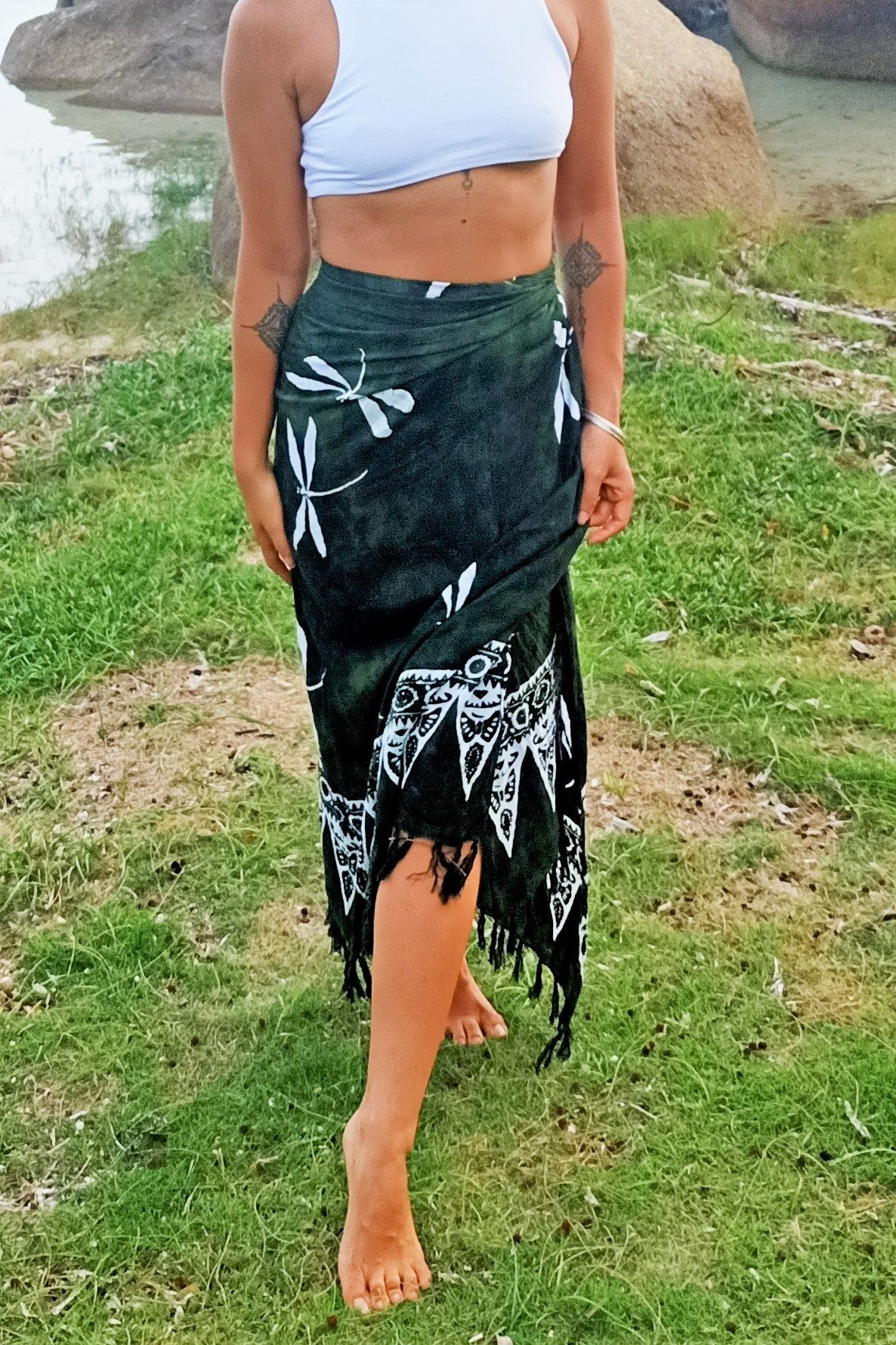 Sarong worn as wrap around beach cover up skirt. Green background with white dragonfly pattern. 